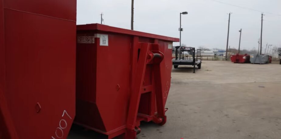 Red roll-off dumpster staged at the Pine Dumpster Co yard in Longview, TX