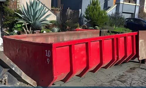 Red roll-off dumpster delivered to a residential yard in Longview, TX